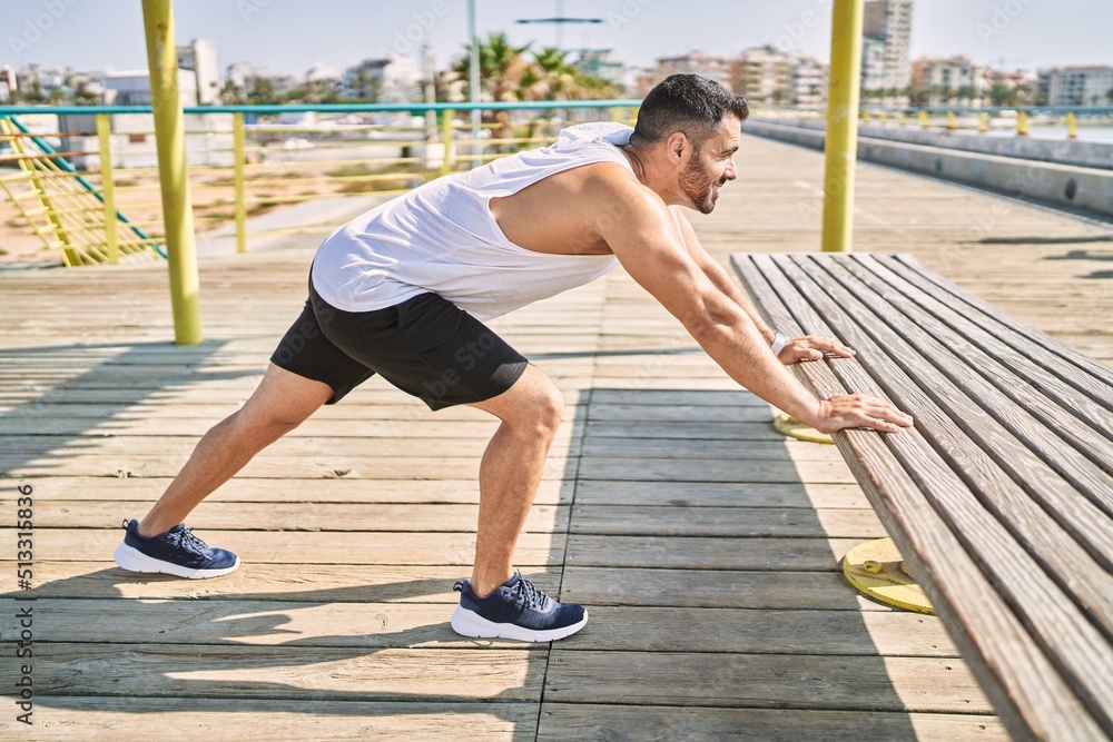 Obraz premium Hispanic man stretching after working out outdoors on a sunny day