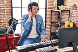 Young non binary man musician playing piano keyboard at music studio