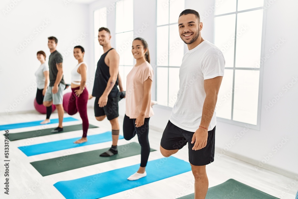 Naklejka premium Group of young hispanic people smiling happy stretching at sport center.