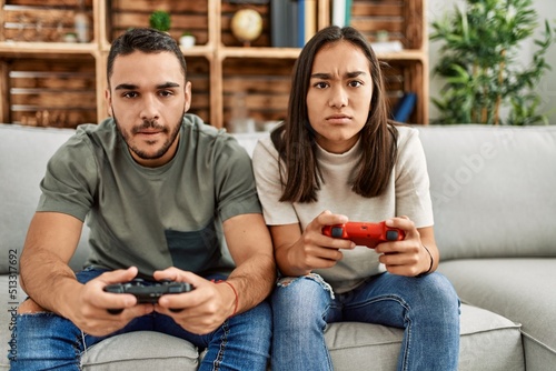 Young latin couple frustrated playing video game at home.