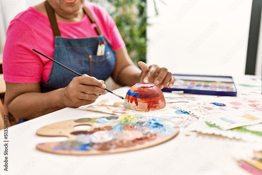Fototapeta premium Senior african american woman painting clay ceramic at art studio