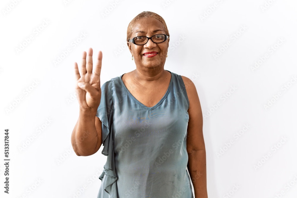 Naklejka premium Mature hispanic woman wearing glasses standing over isolated background showing and pointing up with fingers number four while smiling confident and happy.