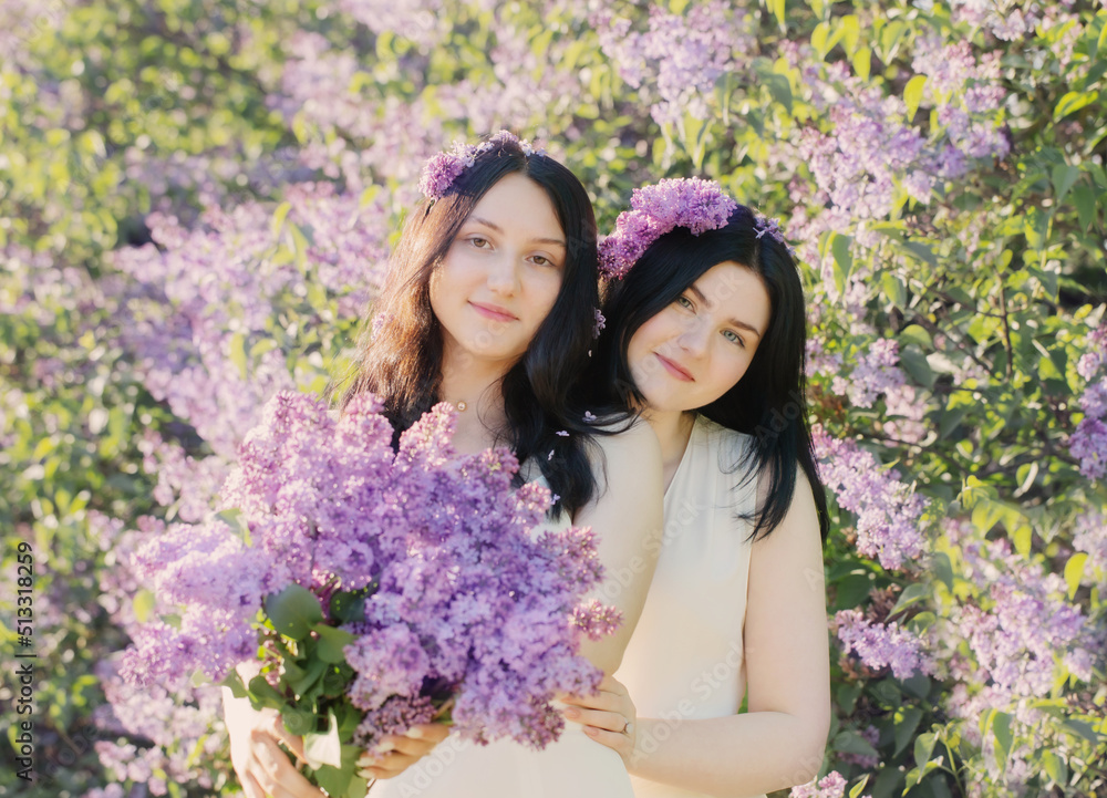 Fototapeta premium two young girls with blooming lilac in sunlight