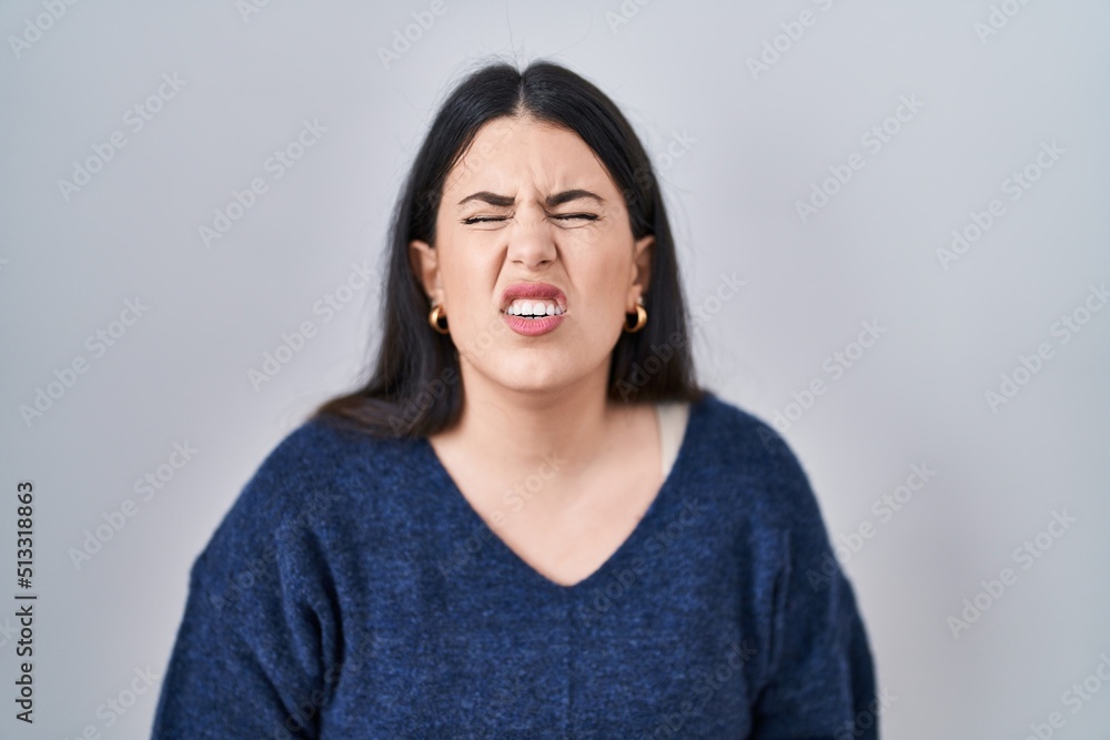 Young brunette woman standing over isolated background with hand on stomach because indigestion, painful illness feeling unwell. ache concept. Young brunette woman standing over isolated background with hand on stomach because indigestion, painful illness feeling unwell. ache concept.