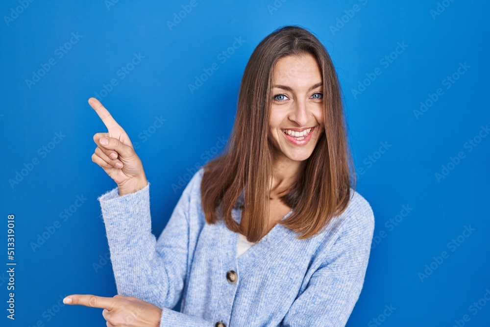 Young woman standing over blue background smiling and looking at the camera pointing with two hands and fingers to the side. Young woman standing over blue background smiling and looking at the camera pointing with two hands and fingers to the side.