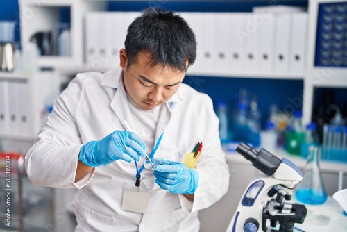 Young chinese man wearing scientist uniform working at laboratory