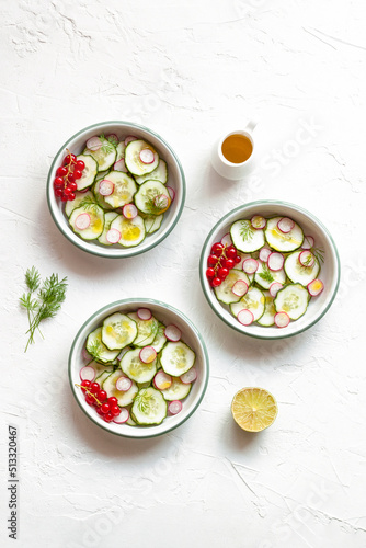 Radish and cucumber salad served in round bowls decorated with red currants