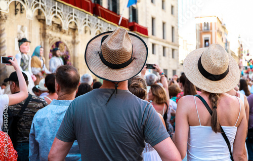 tourists and people from Alicante watching and recording with their mobile phones the parades and dances in the festivities of the bonfires of Alicante, the giants in the background.
