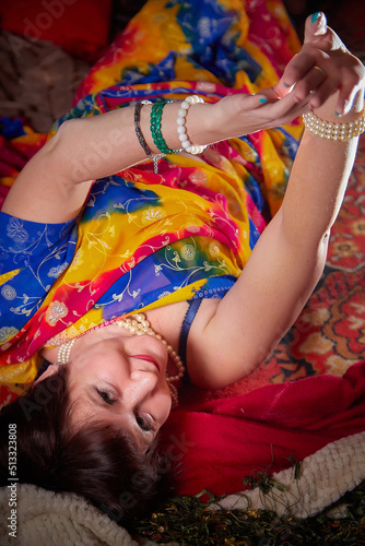 A beautiful European girl with short hair looking like an Arab woman in a red room in a harem. Photo shoot of an oriental style odalisque. A model poses in a sari