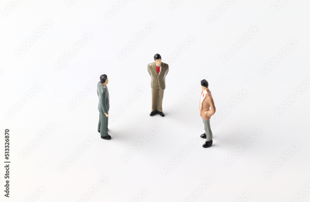 Three miniature people discussing work ideas. Team work concept. Three miniature people discussing work ideas. Team work concept.
