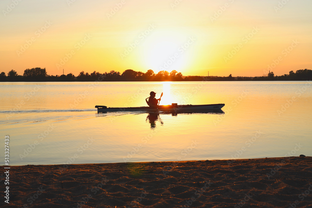 Person kayaking on a lake at sunset