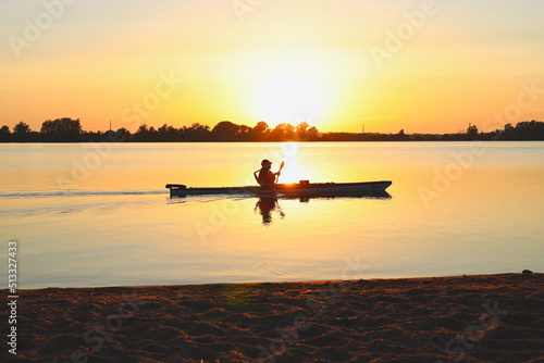 Person kayaking on a lake at sunset
