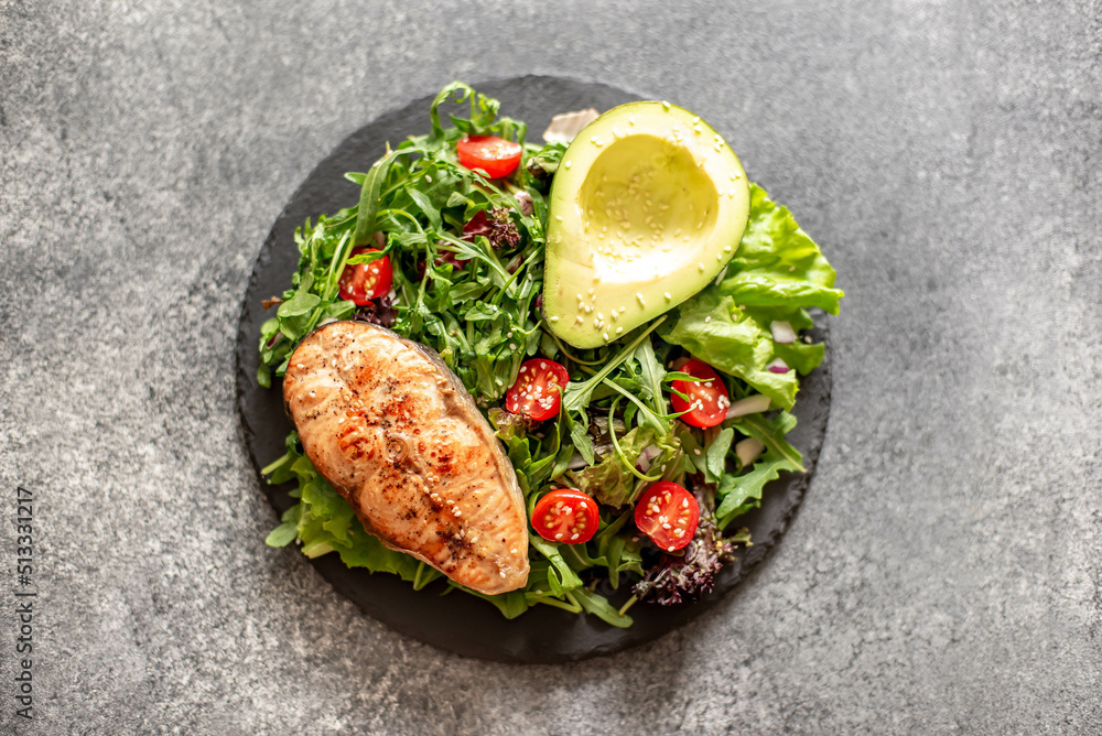 grilled salmon steak and fresh green vegetable tomato salad with lettuce and avocado on stone background grilled salmon steak and fresh green vegetable tomato salad with lettuce and avocado on stone background