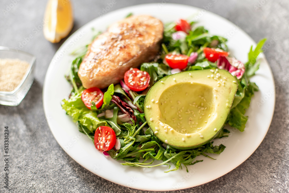 grilled salmon steak and fresh green vegetable tomato salad with lettuce and avocado on stone background grilled salmon steak and fresh green vegetable tomato salad with lettuce and avocado on stone background