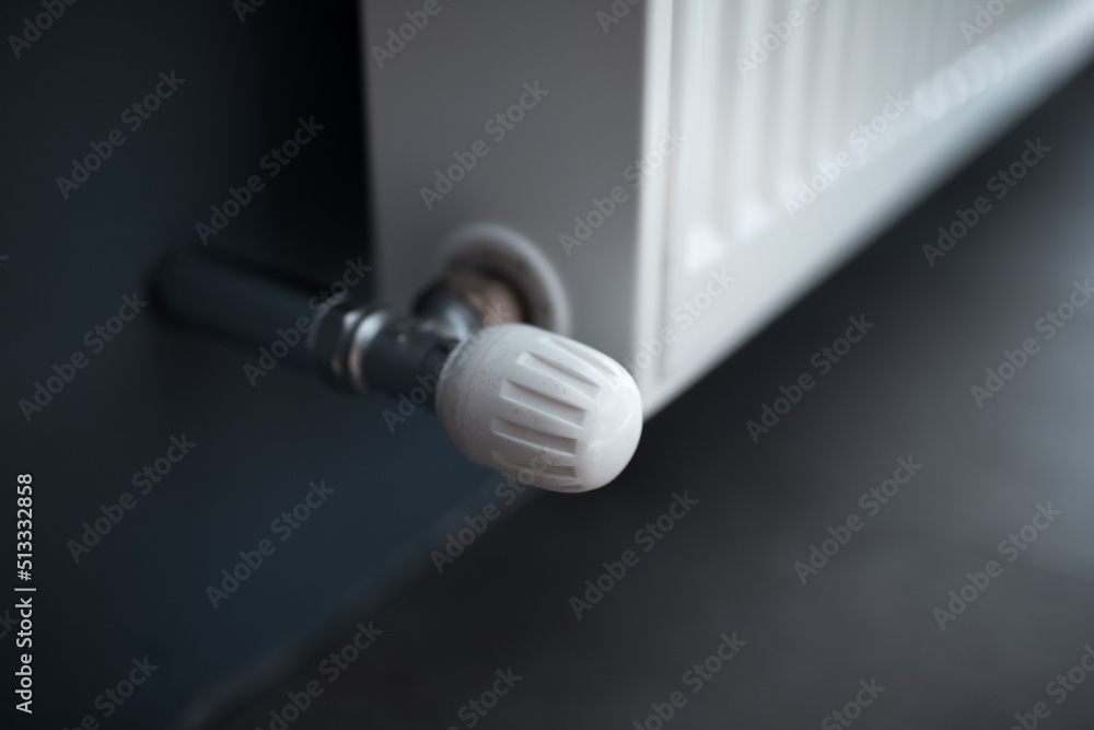 Close-up of valve of heating radiator of white on a grey wall. Close-up of valve of heating radiator of white on a grey wall.