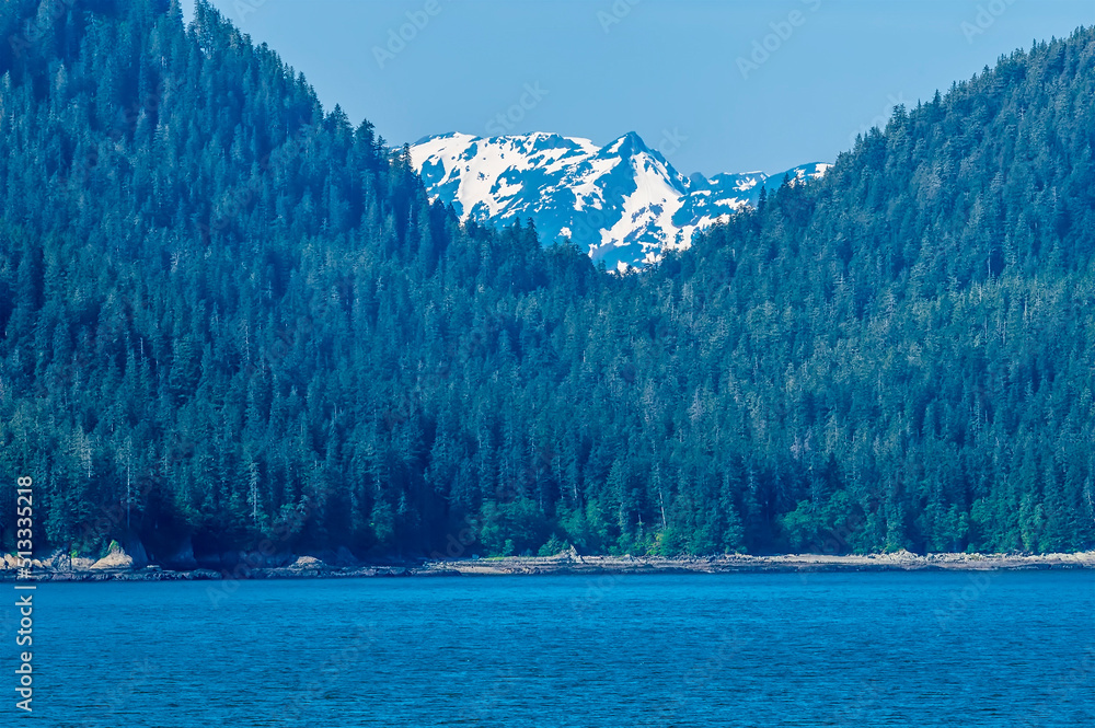 A view of forested hills on the shoreline of the Gastineau Channel approaching Juneau, Alaska in summertime