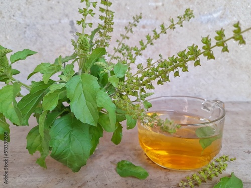 Tulsi tea is served in a cup with fresh leaves on the side of the selected focus.