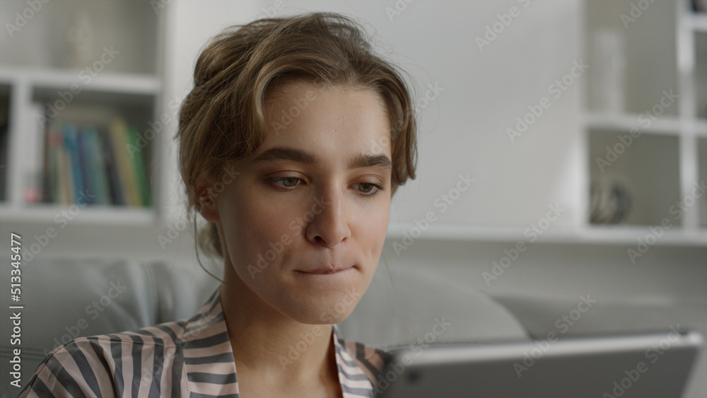 Serious woman browsing internet online biting lips in living room close up. Serious woman browsing internet online biting lips in living room close up.