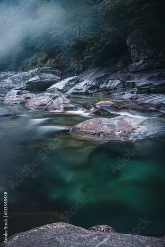 Atmosphärischer Naturhintergrund mit riesigen Steinen im Bergfluss. Große Felsen im mächtigen Wasserstrom, Nahaufnahme. Naturhintergrund mit Wald. Dunkel türkisblauer Fluss mit Steinen.