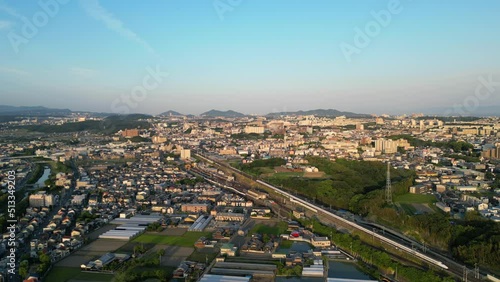 Aerial view of Shinkansen rolling through sprawling Japanese suburbs in late afternoon photo