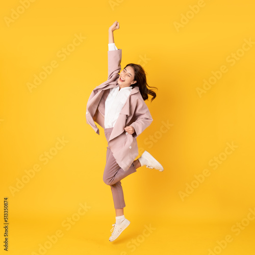 happy asian woman white shirt and blazer on yellow background jumping