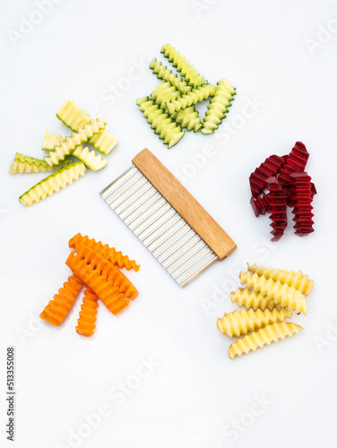 curly knife next to sliced vegetables with a wavy edge