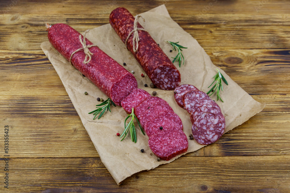 Salami sausages on craft paper on a wooden table Salami sausages on craft paper on a wooden table
