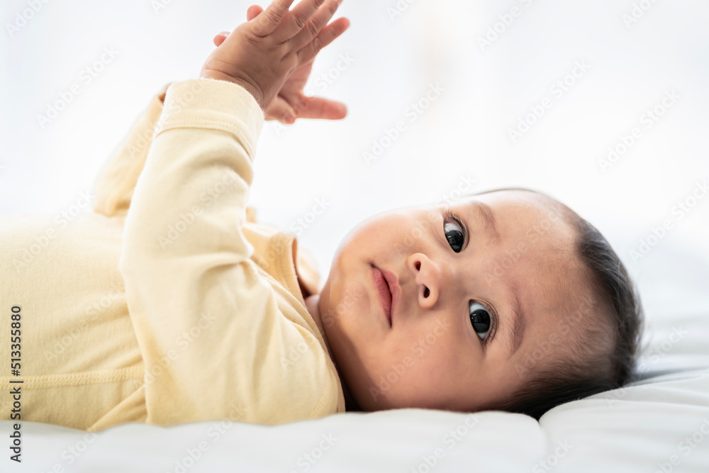 Asian baby girl with white skin and big eyes naughty age playing on the bed by the bedroom window Asian baby girl with white skin and big eyes naughty age playing on the bed by the bedroom window
