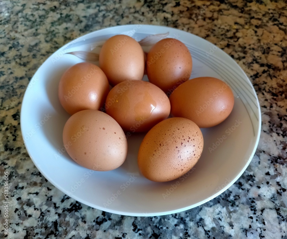 White plate with seven brown eggs. White plate with seven brown eggs.