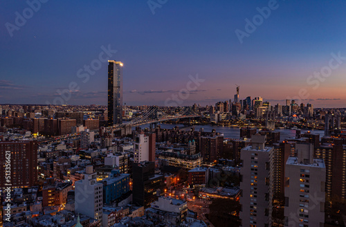 Aerial view of Manhattan Bridge and surrounding buildings in urban neighbourhoods on both riverbanks after sunset. Evening city scene. Manhattan, New York City, USA