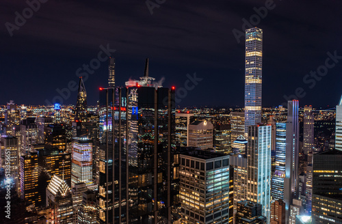 Night city scene with modern high rise buildings in metropolis. Dark glossy glass facade reflecting surrounding lights. Manhattan  New York City  USA