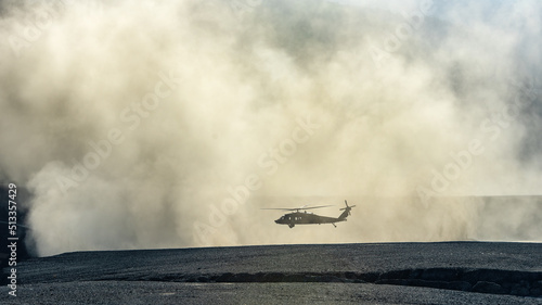 Silhouette of military Black Hawk helicopter landing or taking off in a dust cloud photo