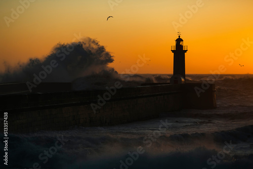 The silhouette of a lighthouse, washed in the twilight by a huge wave.
