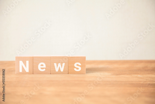 Newsの文字。ニュース。新着情報。木製のテーブルの上に置かれた4つの木製ブロックに書かれている。白い文字。 photo