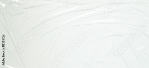 Transparent plastic wrap on white color background. Crumpled wrinkled plastic cellophane. Reflecting light and shadow on creases and folds in plastic surface. Texture overlay effect template