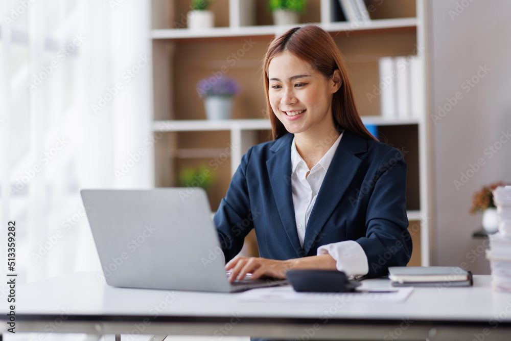 Asian Business woman using calculator and laptop for doing math finance on an office desk, tax, report, accounting, statistics, and analytical research concept Asian Business woman using calculator and laptop for doing math finance on an office desk, tax, report, accounting, statistics, and analytical research concept
