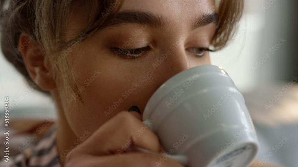 Hand holding coffee cup closeup. Relaxed girl enjoy morning beverage on couch Hand holding coffee cup closeup. Relaxed girl enjoy morning beverage on couch