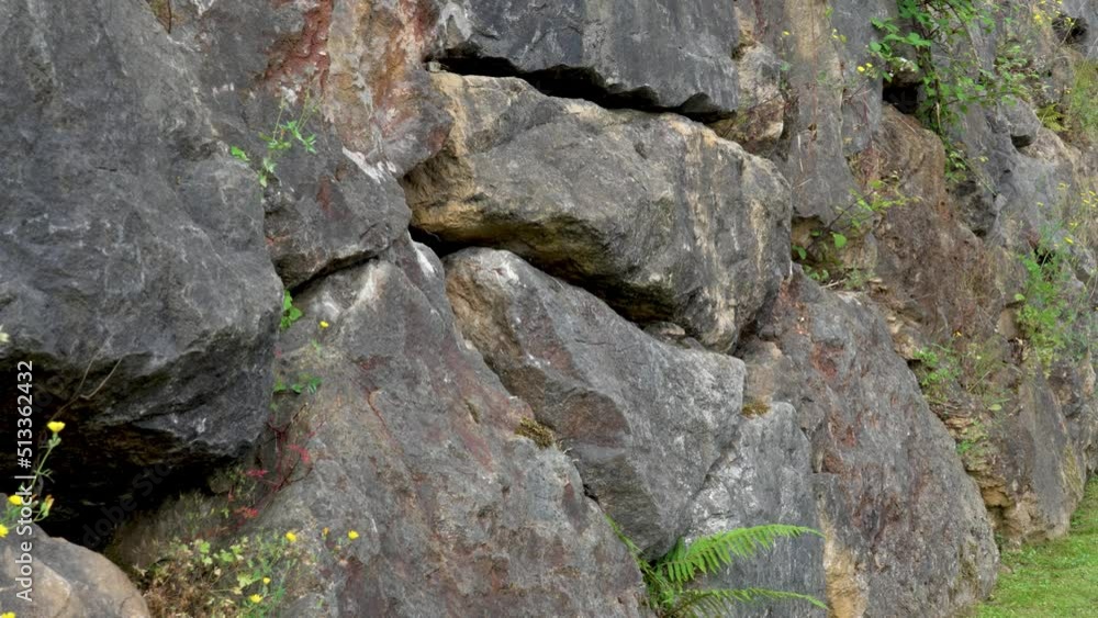 Dark boulder rocks stacked in retaining stone wall outdoors with grass close up. Nature strength concept Dark boulder rocks stacked in retaining stone wall outdoors with grass close up. Nature strength concept