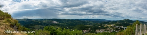 Panoramic view of green mountains of Crni Kal village under a cloudy sky in Slovenia photo