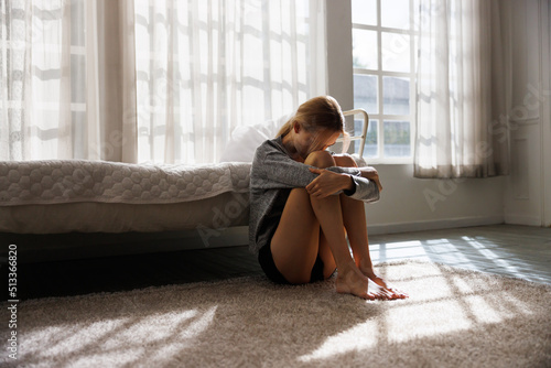 Принти на полотні disappointed and cry woman sitting on the floor near the bed with light and shadow, lost on unpleasant thoughts with life troubles, break up or divorce