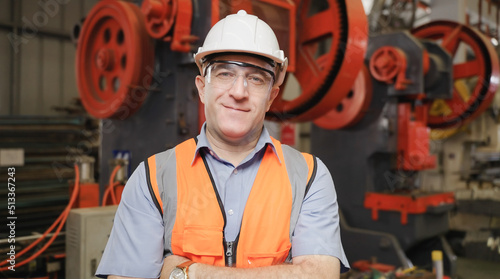 Portrait of happy professional heavy industry male engineer confident wears safety goggles and hard hat standing and arms crossed in factory.