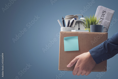 Fired office worker carrying personal belongings in a box photo