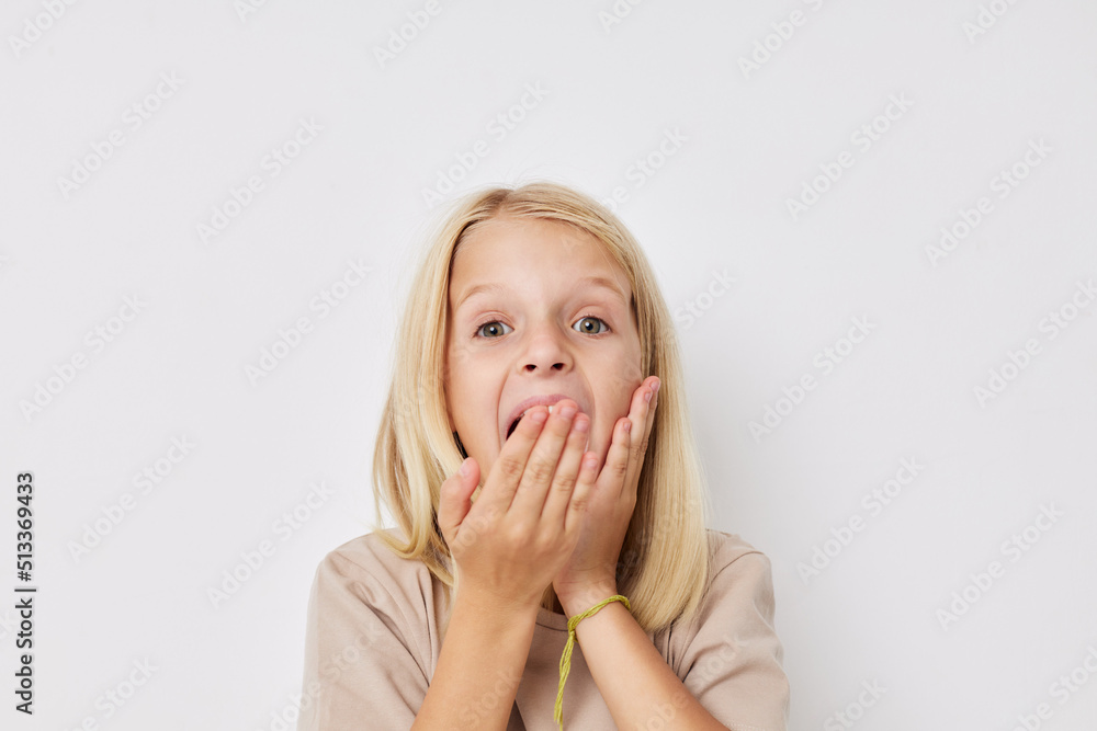 Positive little girl beige t-shirts grimace on a light background Positive little girl beige t-shirts grimace on a light background