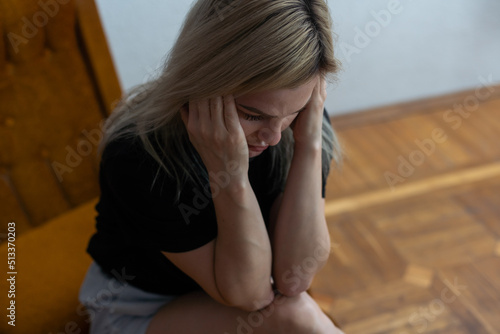 Shot of a young woman holding her head in discomfort due to pain at home.