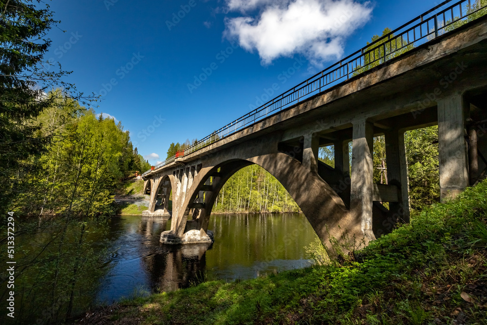 Fototapeta premium An ancient arched railway bridge over the Yanisjoki River. Railway bridge in Karelia.