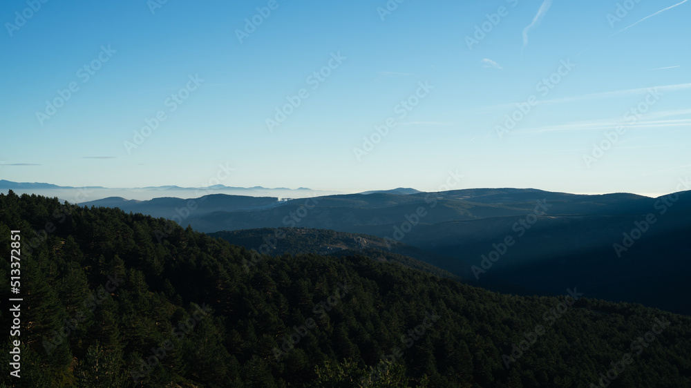 Panorama of a valley  covered by forest with sunbeams coming through the mountains