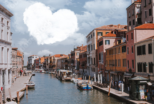 Cloud in the shape of a heart in the sky over the city. Fabulous cityscape overlooking the canal with boats and people walking the streets of Venice. A wonderful tourist day.