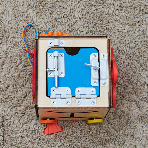 Busyboard cube for infant baby on the nursery floor. Educational toys for children, wooden gamepanel photo