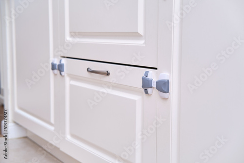 Doors of white cabinets blocked from children, no people. Lock furniture drawers from toddler baby, nobody