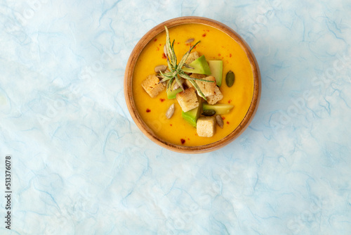 Carrot soup with avocado, toasted seeds, bread, garlic and rosemary in a bowl